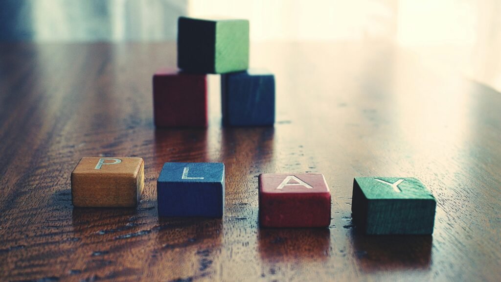 A vibrant still life of wooden alphabet blocks spelling 'PLAY' on a wooden surface.